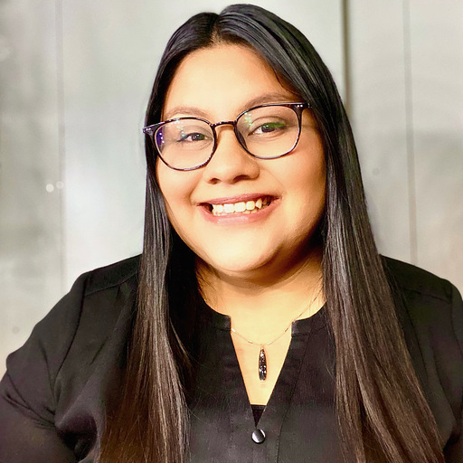 Clarissa Guzman, smiling standing in front of a neutral background.